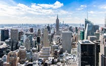 A stunning aerial view of New York City's skyline featuring the iconic Empire State Building under a bright blue sky.